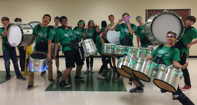 Marching band drummers in custom shirts performing with bass drums and tenors