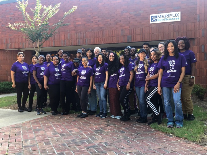 Group of both women and men wearing purple shirts indicating they are microbiologists